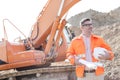 Confident architect holding hardhat and blueprints at construction site Royalty Free Stock Photo