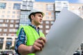 Confident architect holding rolled up blueprints at construction site outdoors Royalty Free Stock Photo