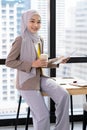 Confident Asia Muslim Islam businesswomen executive working in the modern office holding a cup of coffee and paper chart sitting