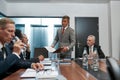 Confident asian businessman in formal wear holding some document and discussing project results with multicultural team Royalty Free Stock Photo