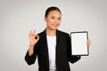 Confident Asian businesswoman showing an 'okay' sign while holding a tablet with a blank screen Royalty Free Stock Photo