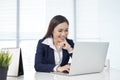 Confident asian businesswoman sitting by desk with laptop in off Royalty Free Stock Photo