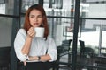 Confident Asian businesswoman standing and holding coffee cup in office. Leader business woman concept. Royalty Free Stock Photo