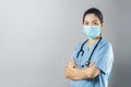 Asian Female doctor with protective face mask standing with arms crossed on grey background Royalty Free Stock Photo