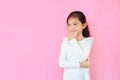 Confident asian little kid girl smiling with crossed arms and touch chin looking out on pink background with copy space. Smart and Royalty Free Stock Photo