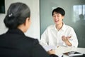 Confident Asian male candidate telling about his career experiences to a job recruiter Royalty Free Stock Photo