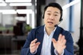 Professional asian businessman in blazer speaking with headset in modern office Royalty Free Stock Photo