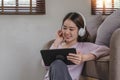 Confident asian woman listening to music with earphones and use tablet while relaxing of work in the office at home. Royalty Free Stock Photo