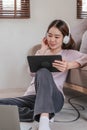 Confident asian woman listening to music with earphones and use tablet while relaxing of work in the office at home. Royalty Free Stock Photo