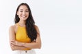 Confident, attractive young outgoing asian woman in yellow top, smiling friendly and happy as cross hands chest, posing Royalty Free Stock Photo