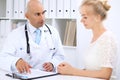 Confident bald doctor man consults his female patient Royalty Free Stock Photo