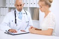 Confident bald doctor man consults his female patient Royalty Free Stock Photo