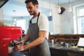Male barista operating red espresso machine portafilter on counter at coffee shop using tablet Royalty Free Stock Photo