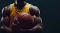 Confident basketball player holding ball, close-up on muscular arms in a yellow jersey. Dark background highlights Royalty Free Stock Photo