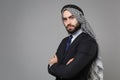 Confident bearded arabian muslim businessman in keffiyeh kafiya ring igal agal classic black suit shirt isolated on gray