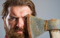 Confident bearded man with axe near face. Serious lumberjack. Sharp blade. Male with ax. Closeup portrait.