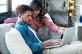 Confident beautiful couple using computer while sitting on the couch at home Royalty Free Stock Photo