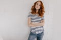 Confident beautiful lady in jeans standing with arms crossed. Serious red-haired woman isolated on Royalty Free Stock Photo