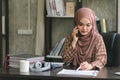 A confident,beautiful, professional, millennial Muslim Asian businesswoman wearing a brown hijab is working remotely