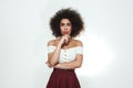 Confident and beautiful. Young afro american woman with curly hair is holding hand on chin and looking at camera while Royalty Free Stock Photo