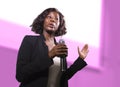 Confident black African American business woman with microphone speaking in auditorium at corporate event or seminar giving Royalty Free Stock Photo