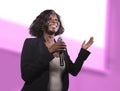 Confident black afro American business woman with microphone speaking in auditorium at corporate event or seminar giving Royalty Free Stock Photo