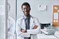 Confident black doctor leaning on glass wall in office smiling at camera Royalty Free Stock Photo