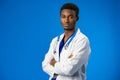 Confident black doctor posing over blue studio background. Royalty Free Stock Photo