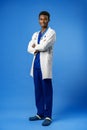 Confident black doctor posing over blue studio background. Royalty Free Stock Photo