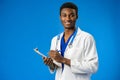 Confident black doctor posing over blue studio background. Royalty Free Stock Photo