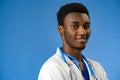 Confident black doctor posing over blue studio background. Royalty Free Stock Photo