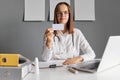 Confident brown haired woman doctor holding blank business or visit card nurse wearing white lab coat and stethoscope looking at Royalty Free Stock Photo