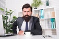 So confident. Brutal look of hipster man. Hipster sit at work desk. Businessman wear hipster beard. Bearded man in