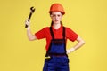 Confident builder woman holding adjustable wrench, looking at camera with serious expression.