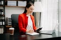 Confident business expert attractive smiling young woman typing laptop ang holding digital tablet on desk in office Royalty Free Stock Photo