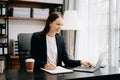 Confident business expert attractive smiling young woman typing laptop ang holding digital tablet on desk in office Royalty Free Stock Photo