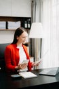 Confident business expert attractive smiling young woman typing laptop ang holding digital tablet on desk in office Royalty Free Stock Photo