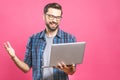 Confident business expert. Confident young handsome man in shirt holding laptop and smiling while standing against pink background Royalty Free Stock Photo