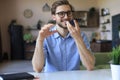 Confident business man in glasses holding smartphone near mouth for recording voice message