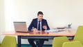 Confident business man typing on smartphone and writing a document while seated at desk in offic