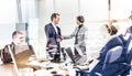 Confident business people shaking hands in moder corporate office. Royalty Free Stock Photo