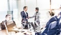 Confident business people shaking hands in moder corporate office. Royalty Free Stock Photo