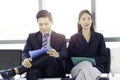 Confident businessman and businesswoman holding File folder during sitting on chair, waiting for job interview in reception hall Royalty Free Stock Photo