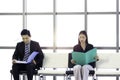 Confident businessman and businesswoman holding file folder during sitting on chair, waiting for job interview in reception hall Royalty Free Stock Photo