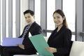 Confident businessman and businesswoman holding file folder during sitting on chair, waiting for job interview in reception hall Royalty Free Stock Photo