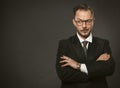 Confident businessman cunningly looks away with his arms crossed. Caucasian middle-aged man standing against a gray wall Royalty Free Stock Photo