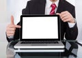 Confident businessman displaying laptop at desk Royalty Free Stock Photo