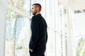 Confident businessman in elegant suite in modern creative office looking in panoramic windows Royalty Free Stock Photo