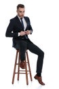 Confident businessman fixing his jacket while sitting on a stool Royalty Free Stock Photo