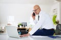 Executive businessman using mobile phone and laptop while working at the office Royalty Free Stock Photo